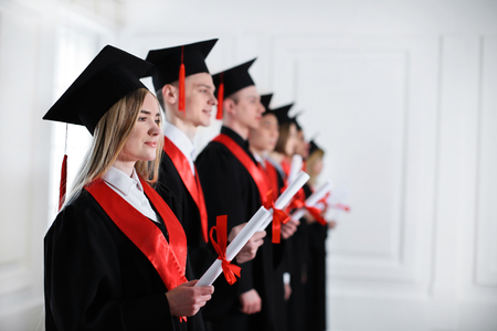 Students in bachelor robes with diplomas indoors. Graduation dayの写真素材