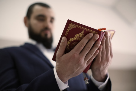 Young Muslim man reading Koran, indoorsの写真素材