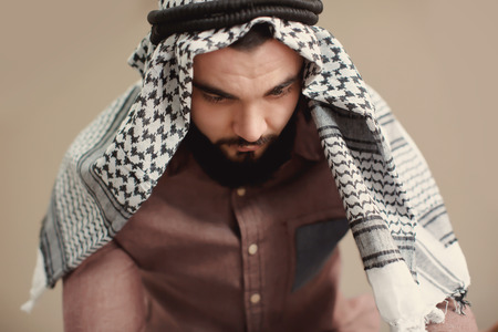 Young Muslim man praying on color background