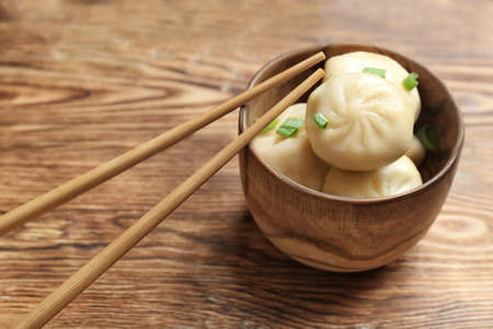 Bowl with tasty baozi dumplings on wooden backgroundの写真素材