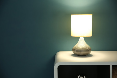 Table with stylish lamp near color wall