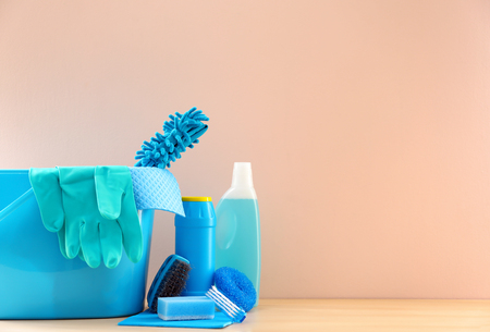 Bucket with cleaning supplies and tools on table near color wallの写真素材