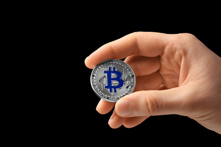 Man holding silver bitcoin on black backgroundの写真素材