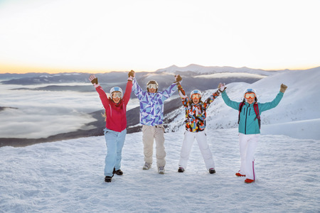 Happy friends standing on snowy mountain peak at ski resort. Winter vacationの写真素材