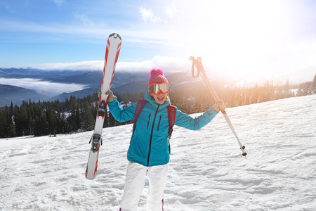 Happy woman on ski piste at snowy resort. Winter vacation