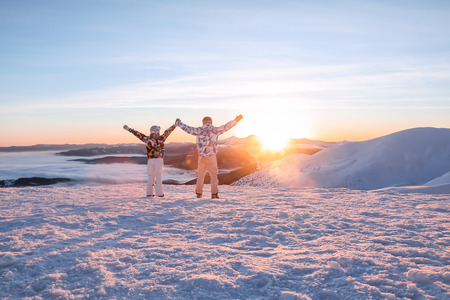 Happy couple enjoying the beauty of sunset at snowy ski resort. Winter vacation