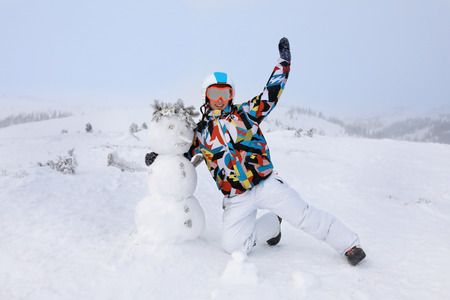 Happy woman with snowman at resort. Winter vacationの写真素材