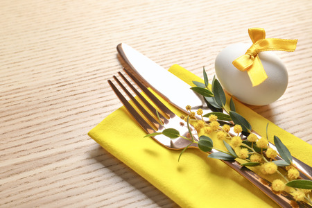 Beautifully decorated cutlery for Easter table setting on wooden background