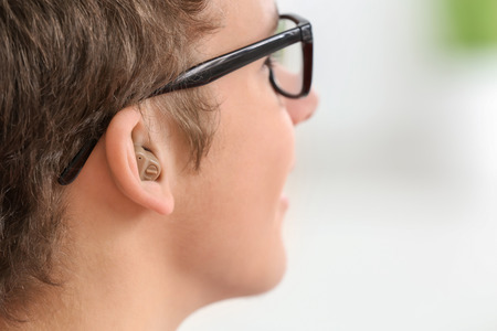 Teenage boy with hearing aid indoorsの写真素材