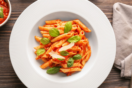 Plate of delicious pasta with tomato sauce on tableの写真素材