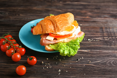 Plate with tasty croissant sandwich on tableの写真素材