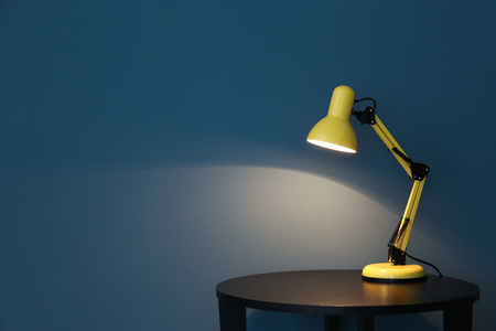 Modern lamp on table near color wallの写真素材