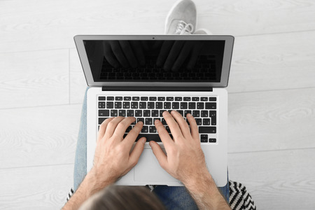 Young man using laptop indoors, top viewの写真素材