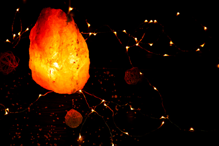Himalayan salt lamp and garland on tableの写真素材
