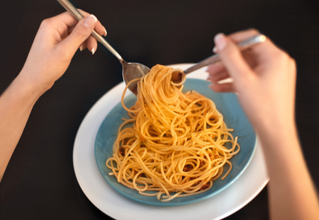 Young woman eating tasty pasta at table, closeupの写真素材