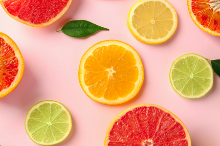 Different cut citrus fruits on color background, top view