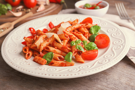 Plate with delicious penne pasta and garnish on tableの写真素材