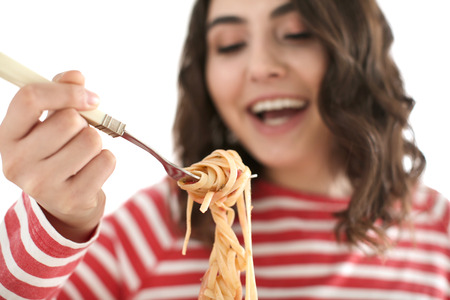 Young woman eating tasty pasta on white background, closeupの写真素材