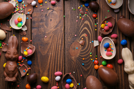 Beautiful Easter composition with chocolate bunnies, eggs and candies on wooden background, top viewの写真素材