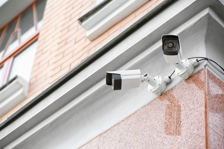 Modern CCTV cameras on wall of building outdoors