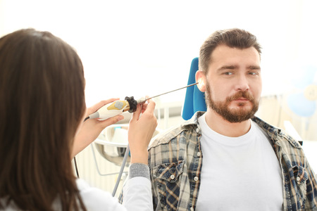 Otolaryngologist examining man's ear with ENT telescope in hospitalの写真素材