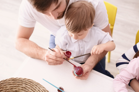 Family painting Easter eggs together at tableの写真素材