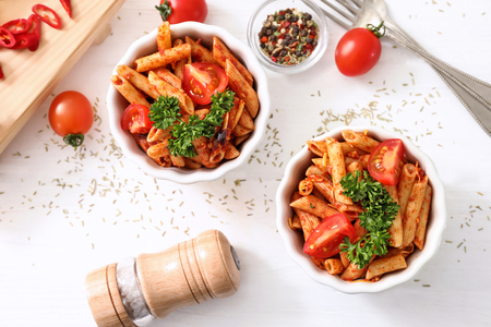 Composition with tasty penne pasta on white tableの写真素材