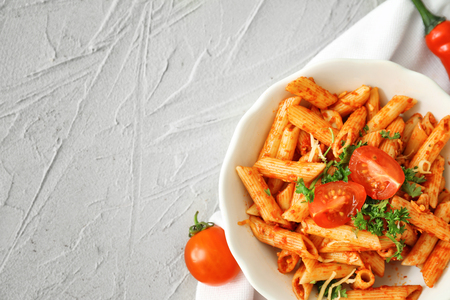 Plate with tasty penne pasta on light textured backgroundの写真素材