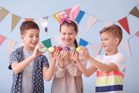 Cute little children with Easter eggs near decorated wallの写真素材