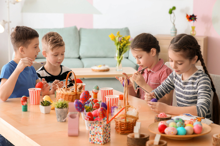 Cute little children painting eggs for Easter at tableの写真素材