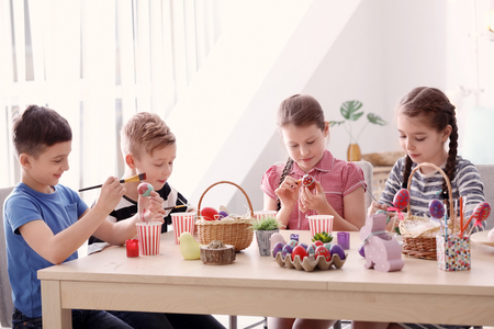 Cute little children painting eggs for Easter at tableの写真素材