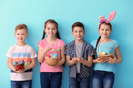 Cute little children with Easter eggs on color backgroundの写真素材