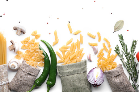 Flat lay composition with uncooked pasta and vegetables on white backgroundの写真素材