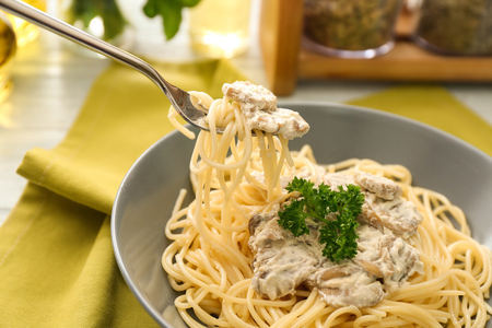 Delicious pasta with mushroom sauce on fork over plateの写真素材