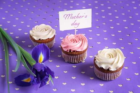 Tasty cupcakes, flower and topper pick with words MOTHER'S DAY on color backgroundの写真素材