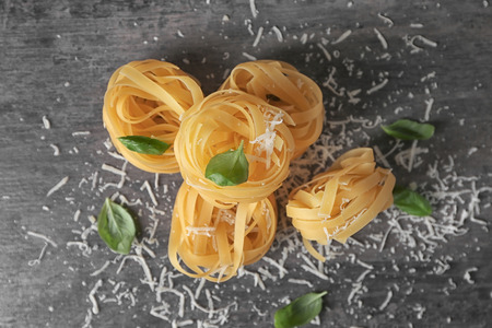 Raw pasta with basil and grated cheese on tableの写真素材