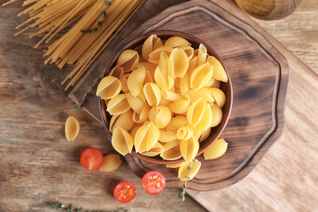 Bowl with raw pasta on tableの写真素材