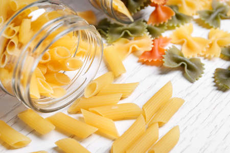 Jar and different raw pasta on tableの写真素材