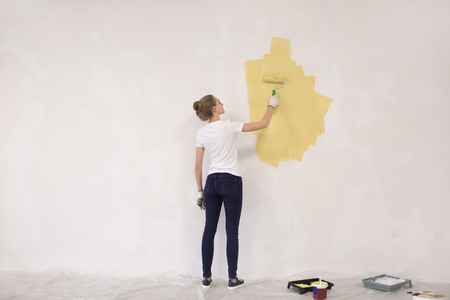 Female decorator painting wall with roller indoorsの写真素材