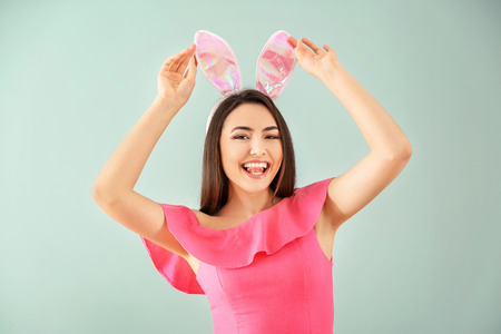 Beautiful young woman with Easter bunny ears on color backgroundの写真素材