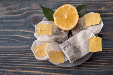 Plate with tea bags and lemon on wooden backgroundの写真素材