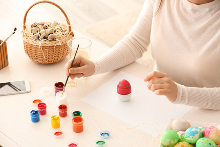 Beautiful young woman painting Easter eggs at home, closeupの写真素材