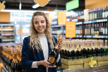 Young woman with bottle of alcohol drink in liquor shop. Small business ownerの写真素材