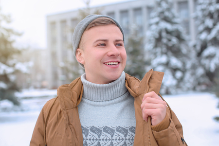 Portrait of happy young man in snowy park on winter vacationの写真素材