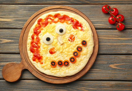 Board with creative pizza on wooden background, top viewの写真素材