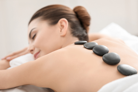 Young woman enjoying stone massage in spa salonの写真素材
