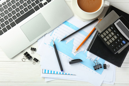 Laptop, cup of coffee and stationery on wooden background, flat lay. Workplace table compositionの写真素材