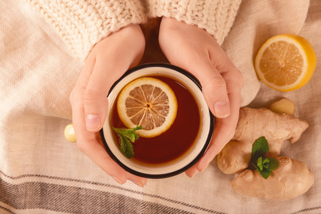 Woman holding mug of hot lemon tea with ginger, top viewの写真素材