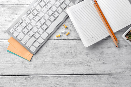 Computer keyboard and stationery on wooden background, flat lay. Workplace table composition