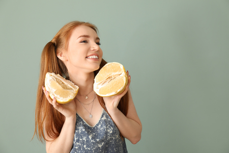 Beautiful young woman with citrus fruit on color backgroundの写真素材